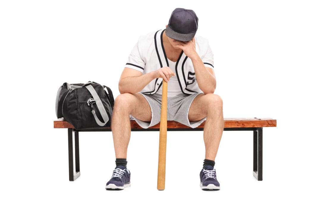 sad young ballplayer sitting on the bench